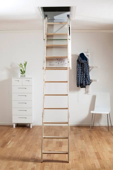 Timber and aluminium folding manual attic ladder extended from a ceiling hatch into a bright minimalist room with a timber floor