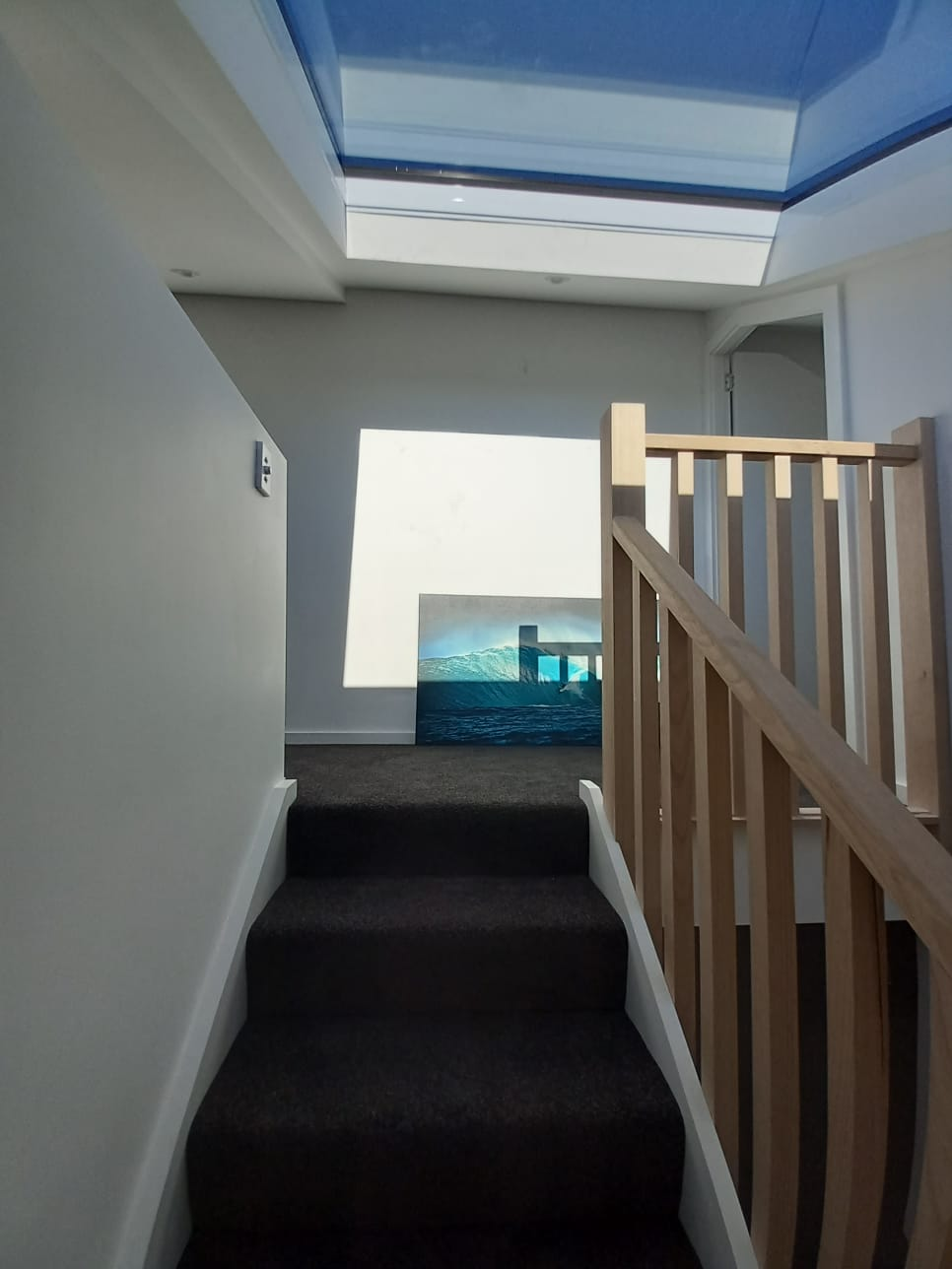 Bronte staircase landing with surf artwork and dark carpet